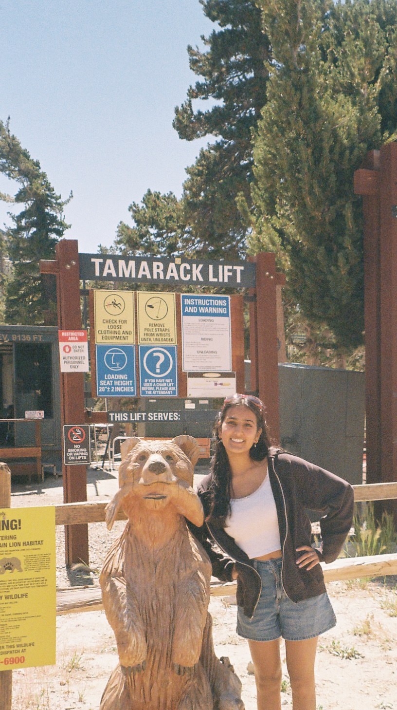 Shalini standing next to a carved wooden bear at the Tamarack Lift
